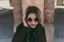 Дівчина в навушниках посміхається на камеру — стокове фото