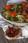 Vue rapprochée du petit panier de poivrons rouges servi près du plat de spaghetti italien — Photo de stock