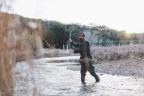 Fisher hombre de pie junto al río y la pesca con caña - foto de stock