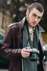 Портрет стильного чоловіка в окулярах з аналоговою камерою на вулиці — стокове фото