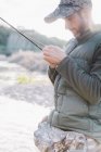 Side view of man preparing hook for fishing at river — Stock Photo