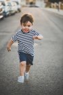 Портрет удивленного мальчика, бегущего с открытым ртом по асфальтовой дороге — стоковое фото