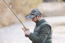 Retrato del hombre preparando anzuelo para pescar en el río - foto de stock