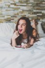 Menina deitada na cama e comendo frutas — Fotografia de Stock