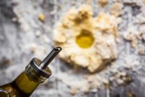 Oben von Flasche, die Öl in Mehlstapel auf ländlichem Holztisch gießt — Stockfoto