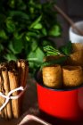 Close up view of red mug with fried honey dough tubes with mint and cinnamon sticks — Stock Photo