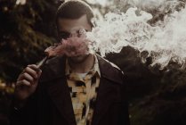 Portrait d'un homme caché face à la fumée d'une bougie de fumée à la main — Photo de stock