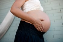 Неузнаваемая беременность держит её живот. Закрыть, профиль животика. — стоковое фото