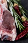 Côtes d'agneau crues sur assiette noire — Photo de stock