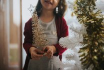 Ernte lächelndes Mädchen mit winzigem dekorativen Weihnachtsbaum — Stockfoto