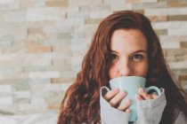 Ingwerfrau trinkt Kaffee aus blauer Tasse — Stockfoto