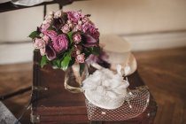 Purple bridal bouquet and hat on vintage suitcase — Stock Photo