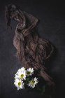 Motif floral avec des fleurs de camomille et tissu de regard brun sur la surface sombre — Photo de stock