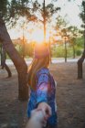 Rückansicht des Mädchens mit lustiger Wollmütze, die im Sonnenuntergangslicht durch Ziehen der Hand führt — Stockfoto