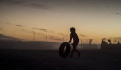 Silhouette spielt mit Reifen — Stockfoto