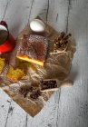 Vue grand angle des tranches de gâteau au citron sur du papier de boulangerie avec des ingrédients sur une table rurale en bois blanc — Photo de stock