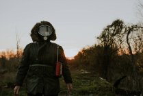 Portrait of man wearing gas mask and standing in field at sunset time — Stock Photo