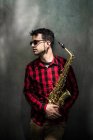 Saxofonist steht mit Instrument und schaut zur Seite — Stockfoto
