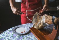 Female hands slicing Serrano ham with knife — Stock Photo