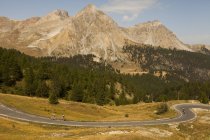 Paesaggio panoramico con ciclisti che cavalcano su strada in montagna — Foto stock