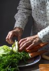 Vue rapprochée des mains prenant des légumes de la pile sur l'assiette — Photo de stock