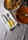 Vue de dessus de fourchette et couteau sur serviette servie près des assiettes avec ragoût et soupe sur nappe rustique — Photo de stock