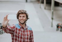Sorridente brunetta uomo prendendo selfie con smartphone sulla scena della strada — Foto stock
