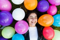 From above woman smiling with eyes closed on grass with balloons. — Stock Photo
