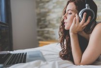 Mulher de gengibre ouvindo música e usando laptop — Fotografia de Stock