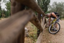 Вид збоку старшого чоловіка, що вигинається над велосипедом і регулює ланцюг велосипедів — стокове фото
