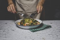 Розрив жінки, що тримає виделку і ложку над італійським зеленим тальятелле з морепродуктами — стокове фото