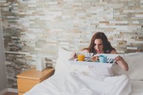 Mädchen im Bett hält Tablett mit Frühstück — Stockfoto