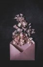 Вид зверху на рожевий відкритий конверт з купою квітів на поверхні каменю — стокове фото