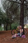 Портрет пожилого человека, смотрящего прочь с книгой в руке на дерево с велосипедным парком позади — стоковое фото