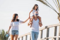 Fröhlicher Vater kümmert Tochter auf Schultern beim Spaziergang mit Frau — Stockfoto