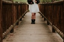 Unterteil eines Mädchens im weißen Kleid auf Holzbrücke — Stockfoto