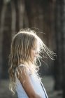 Seitenansicht des blonden kleinen Mädchens, das im Sonnenlicht posiert — Stockfoto