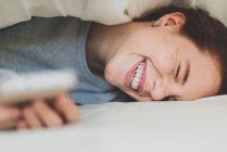 Сміється дівчина лежить під подушкою — стокове фото