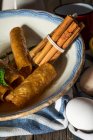 Close up view of late with fried honey dough tubes and cinnamon sticks on towell — Stock Photo