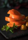 Свіжий нарізаний апельсин з листя м'яти на шифері — стокове фото