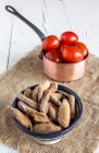Bowl with bread sticks and sauce pot with tomatoes — Stock Photo