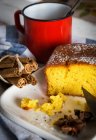 Still life of lemon cake and cinnamon sticks and red mug — Stock Photo