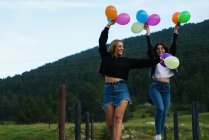 Mulheres festivas correndo com balões na natureza — Fotografia de Stock