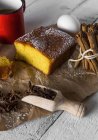 Натюрморт из лимонного торта, коричные палочки и совок анисовой звезды на деревенском столе — стоковое фото