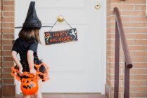 Menina em chapéu de bruxa na frente da porta — Fotografia de Stock