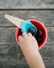 Hand of little girl taking cherry from bowl — Stock Photo