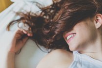 Mujer sonriendo con la cara cubierta de pelo de jengibre - foto de stock