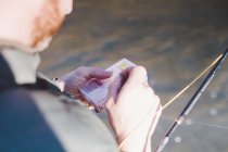 Через плечо вид человека, готовящего крючки для рыбалки — стоковое фото