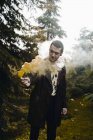 Portrait of young man posing with smoke candle at woods — Stock Photo