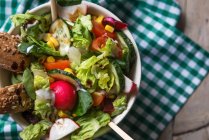 Крупным планом свежего овощного салата в миске с хлебом — стоковое фото